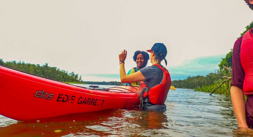 an instructor gives direction to a student in a kayak on an outward bound trip
